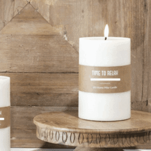 A lit white candle on a wooden surface with a rustic background.